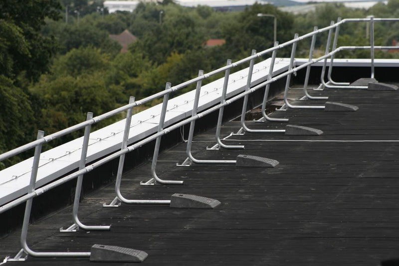 actual photo of roof edge protection system on black roof with trees in background